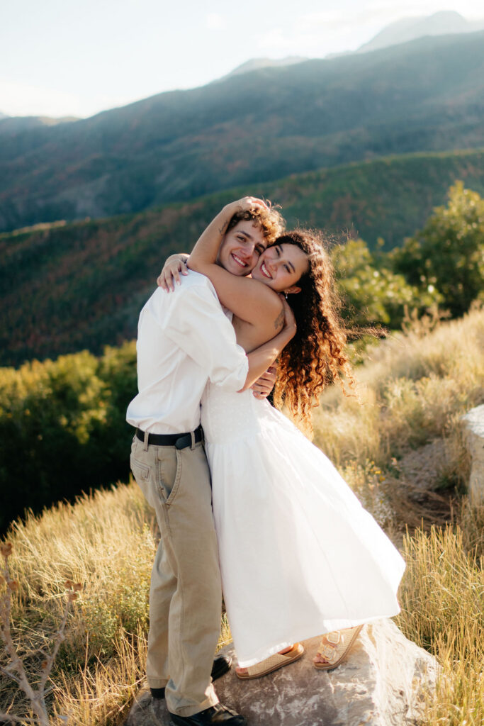 a couple smiles together at an overlook during their fall engagement photos on the alpine loop in american fork canyon with utah engagement photographer sarah mismash