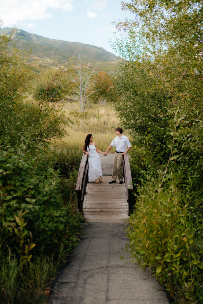 a couple holds hands and leans against a bridge during their september engagement photos in american fork canyon with utah engagement photographer sarah mismash