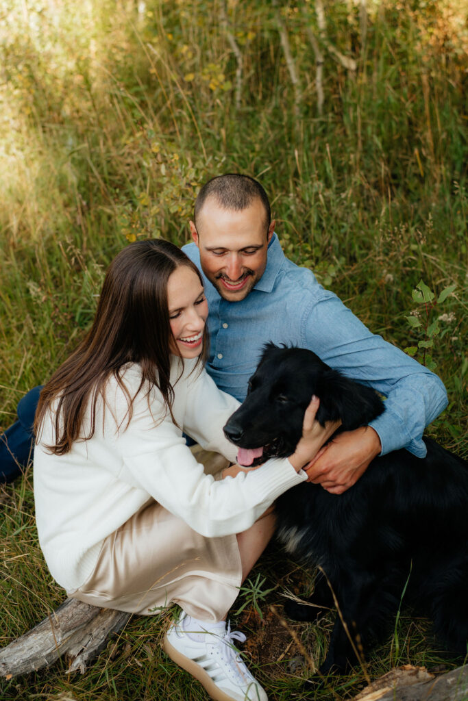 a couple snuggles their dog during their engagement photos on the alpine loop