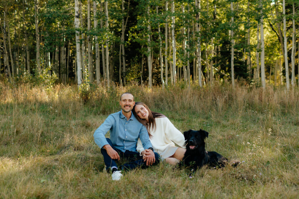 a couple leans together in a field of aspens during their fall engagement photos on the alpine loop