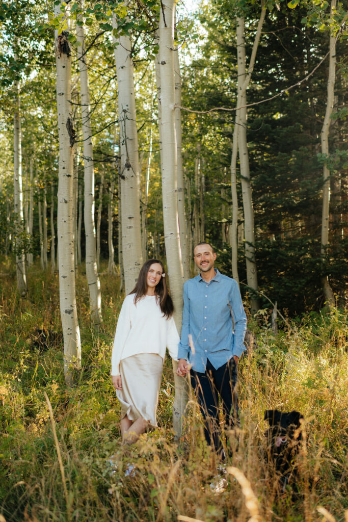a couple leans together in a field of aspens during their fall engagement photos on the alpine loop