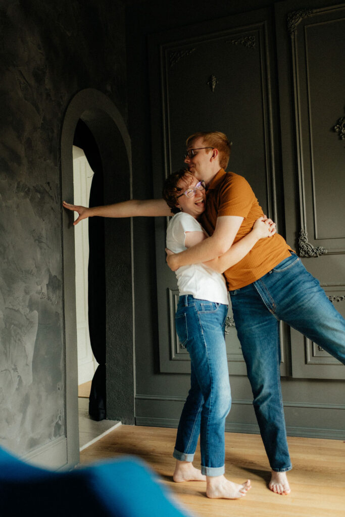 couple falling over during their indoor engagement photos at brightwood house studios in provo utah