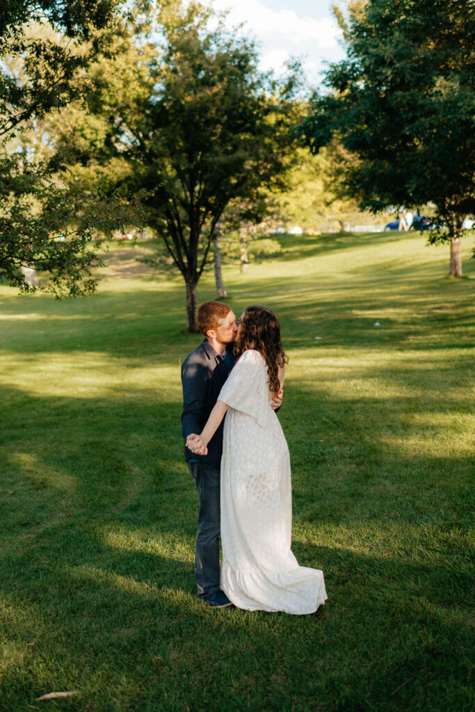 a couple kisses during their september engagement photos at sugarhouse park with slc engagement photographer sarah mismash