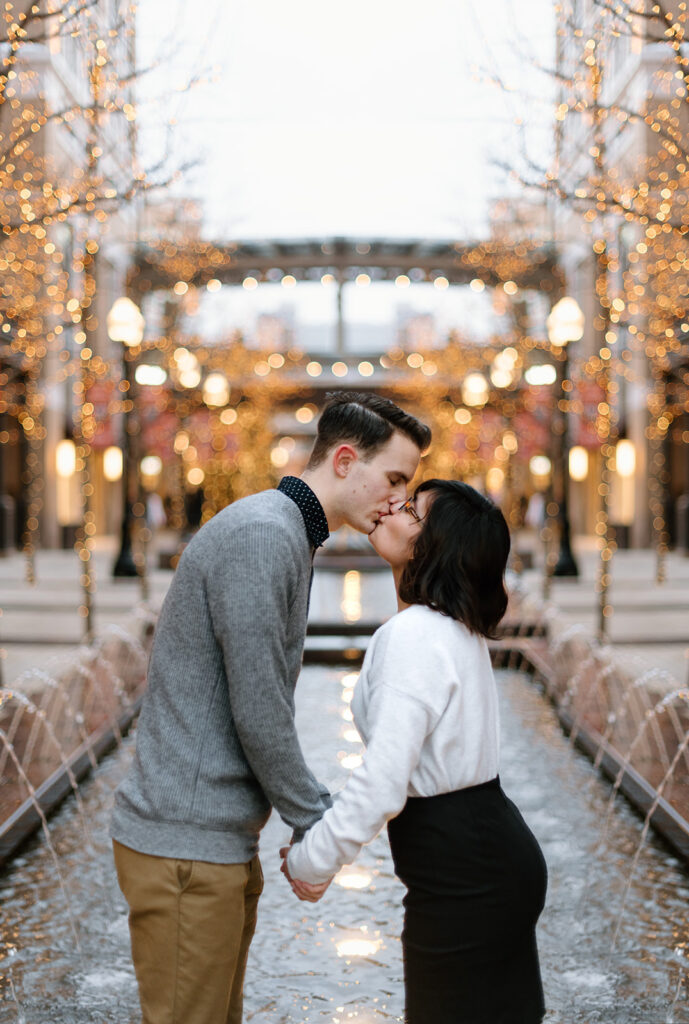 a couple kisses during a winter engagement session at city creek in downtown salt lake, near temple square and the christmas lights