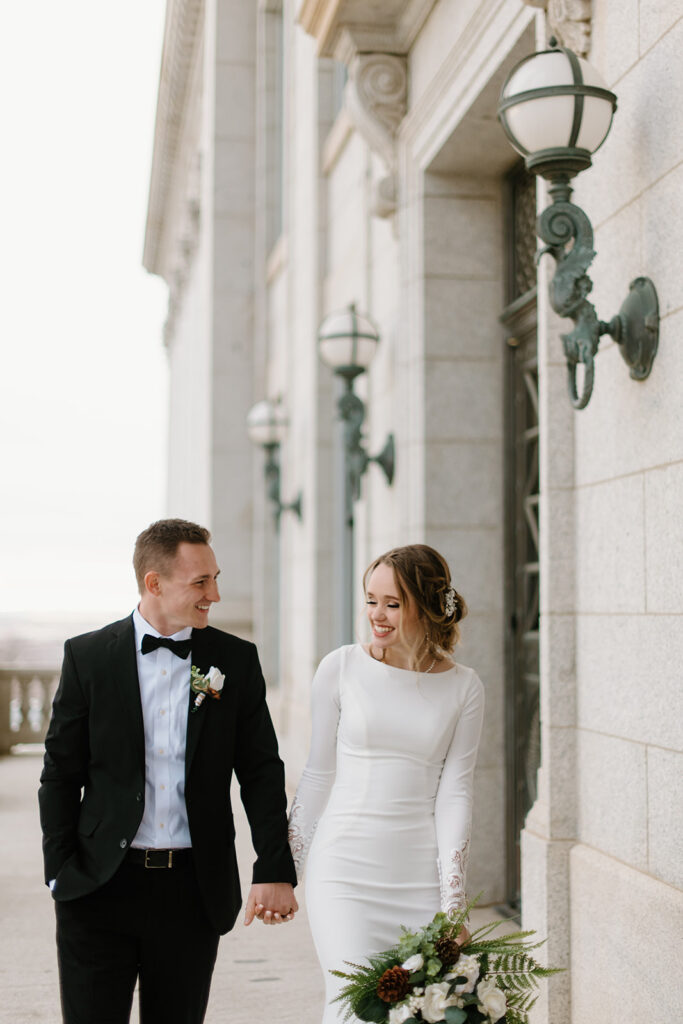 a couple walks across the utah state capitol grounds during a not very snowy bridal session in salt lake city in january