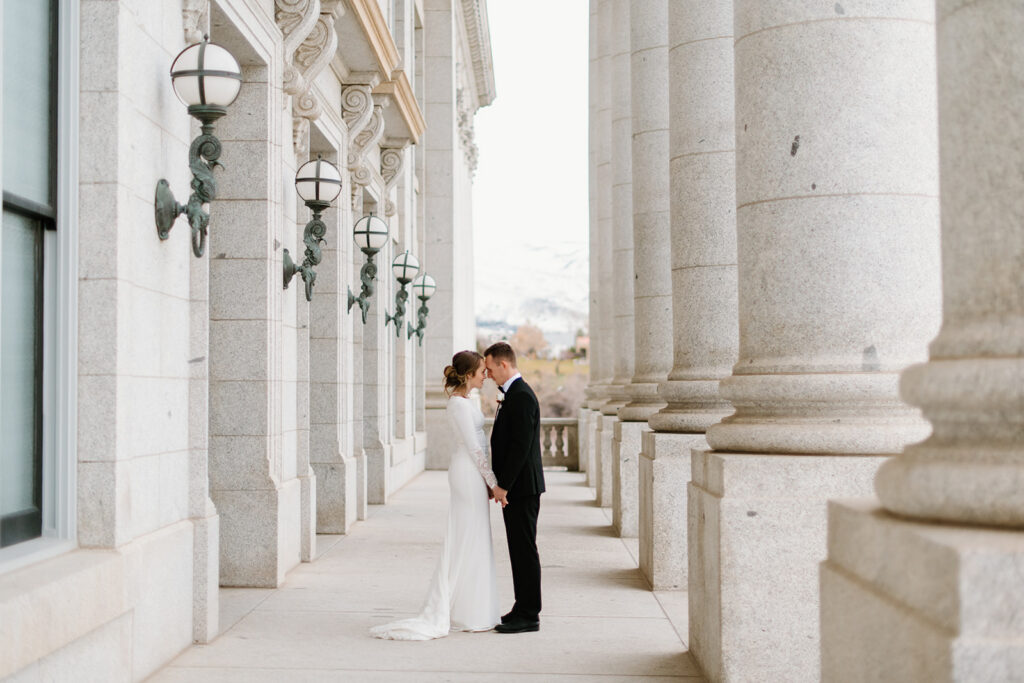 a couple pauses together for a quiet moment during their winter wedding photos at the utah state capitol